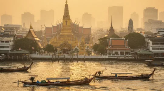 Vue panoramique du fleuve Chao Phraya à Bangkok avec les temples dorés et les bateaux traditionnels sous la brume de chaleur