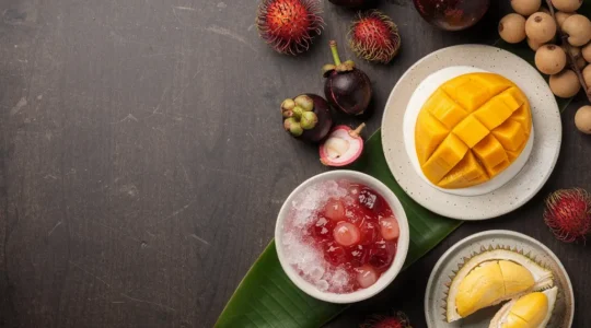 Assortiment de desserts thaïs aux fruits sur une table, avec un espace vide pour le titre.