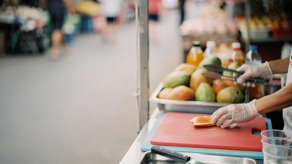Étale de fruits de rue avec planche, couteau et bac d’eau séparés, illustrant une zone de découpe plus sûre.
