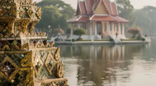 Vue panoramique contrastant l’or et les mosaïques du Grand Palais de Bangkok avec un pavillon sur l’eau à Bang Pa-In, suggérant deux visages de la monarchie thaïlandaise.