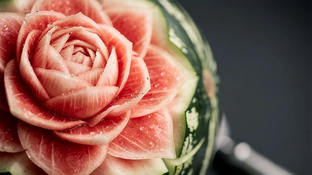 Gros plan d’une pastèque sculptée en pétales de fleur, avec détails de texture et lumière douce.