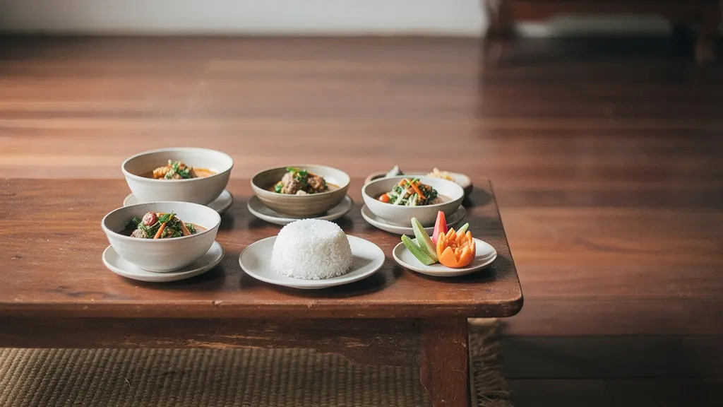 Vue large d’un plateau de petits plats thaïs disposés ensemble sur une table basse, ambiance minimaliste et contemplative.